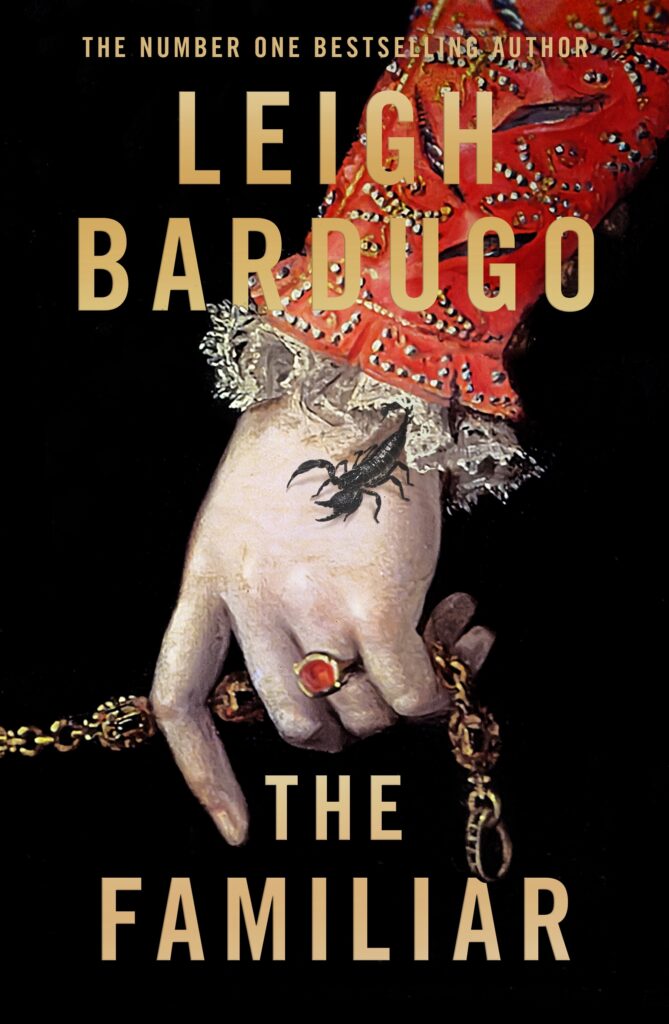 Cover of The Familiar, by Leigh Bardugo, features a pale hand holding a chain (maybe a rosary?), wearing a ring with a red stone, and a scorpion crawling out of the lacy cuff of a gold-embroidered red sleeve.